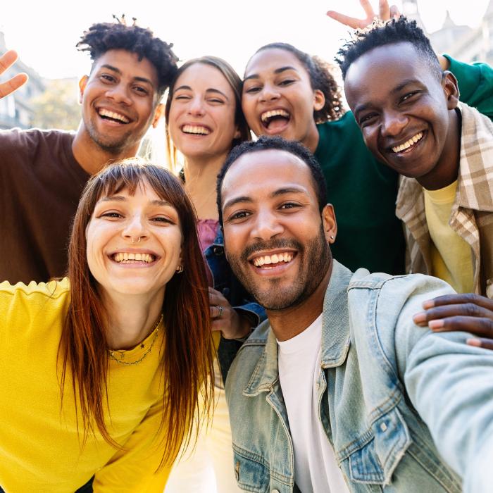 group of people of various races and genders smiling at the camera