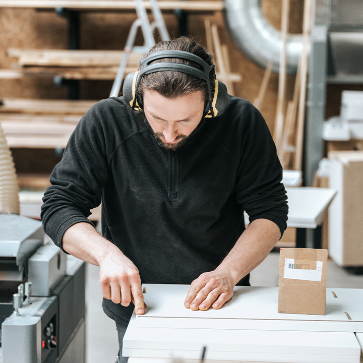 worker measuring item with hearing protection