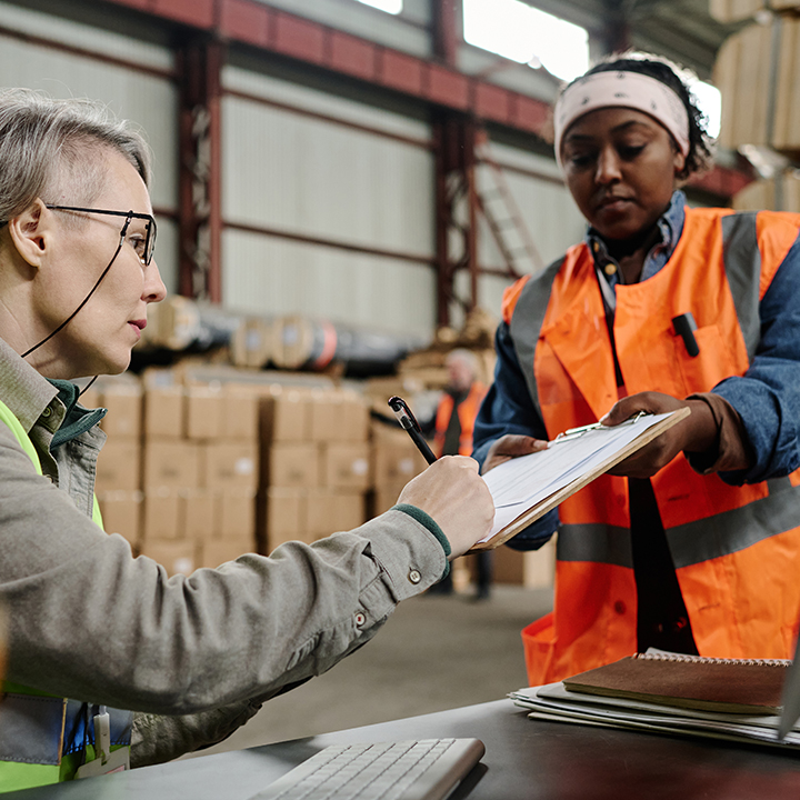 worker signing paper on clipboard held by other worker