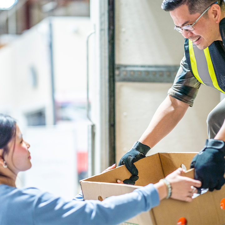 worker handing box to another worker from a truck 