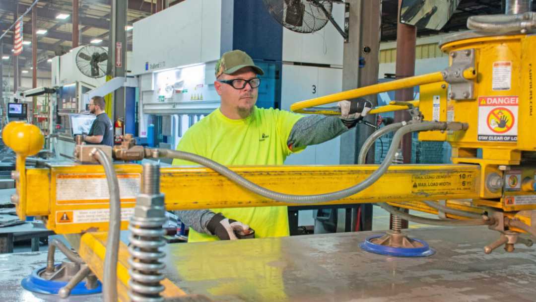 Machine operator wearing a yellow shirt and hardhat 