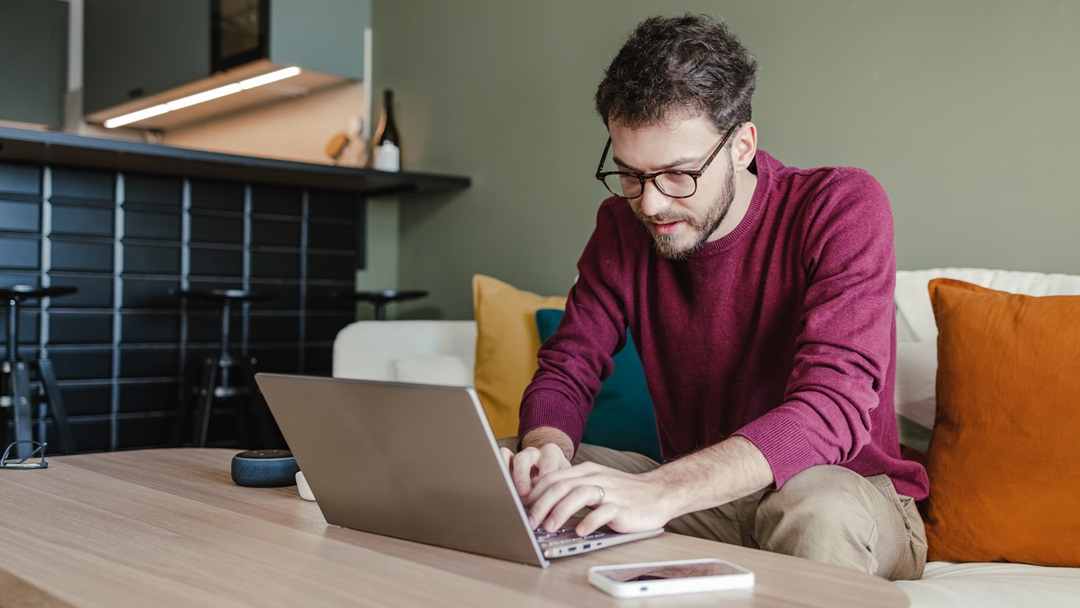 Man working on a laptop while sitting on a couch