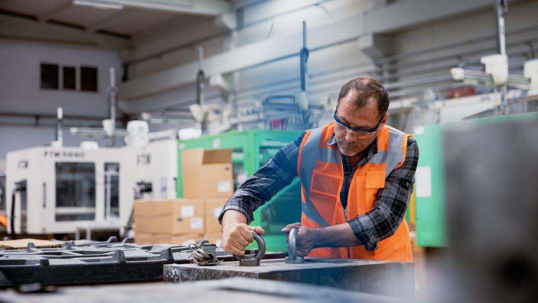 Manufacturing worker in reflective vest working machinery