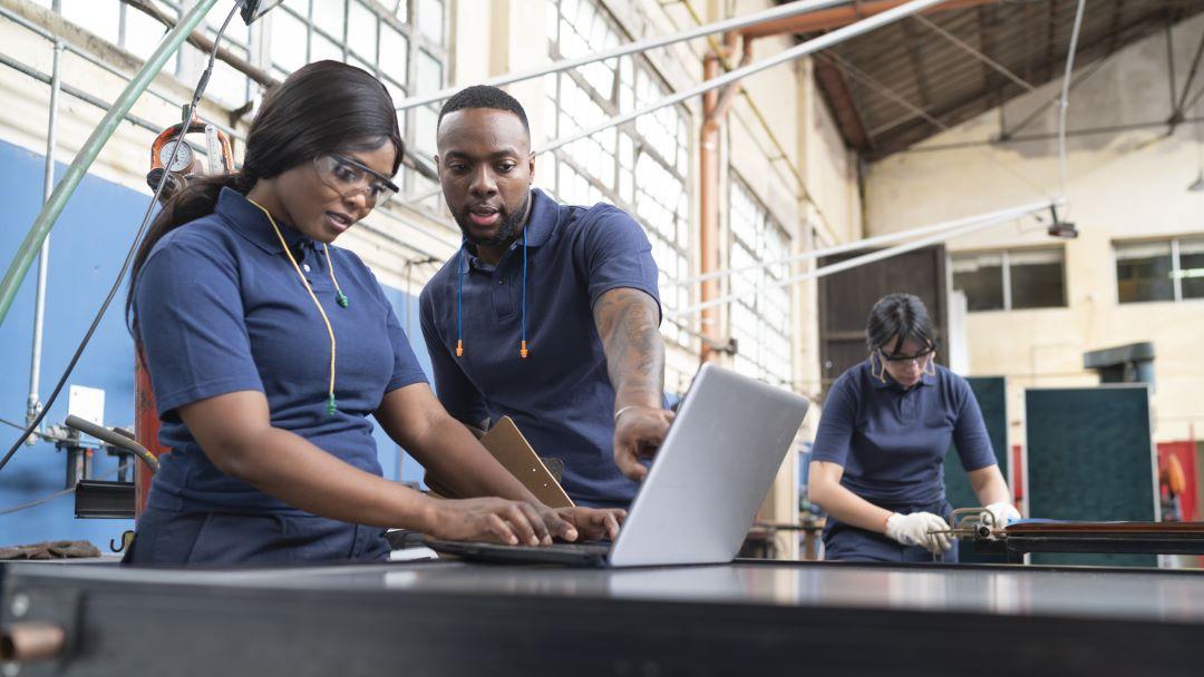 Two manufacturing workers looking at a laptop together