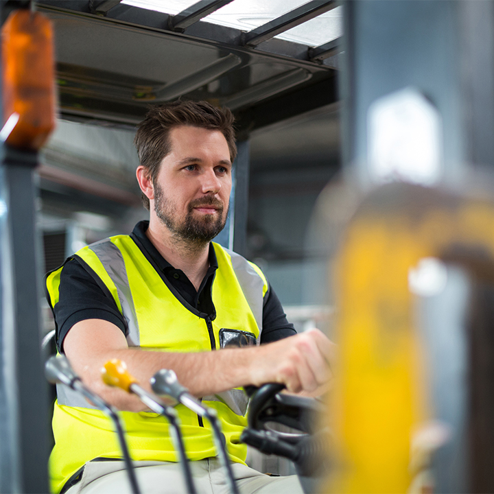 man in a reflective vest operating a forklift