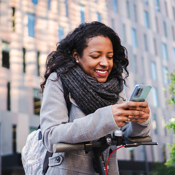 woman walking down city street looking at smartphone