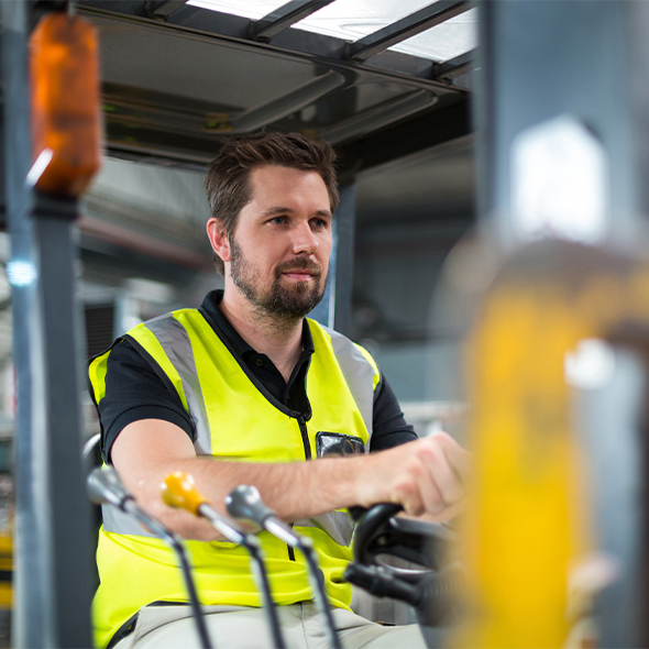 man in a reflective vest operating a forklift