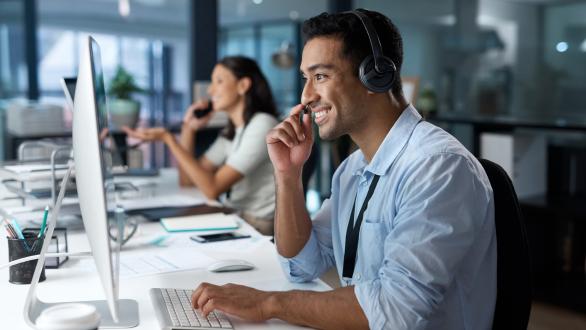 An office worker with headphones on, focusing on his work.